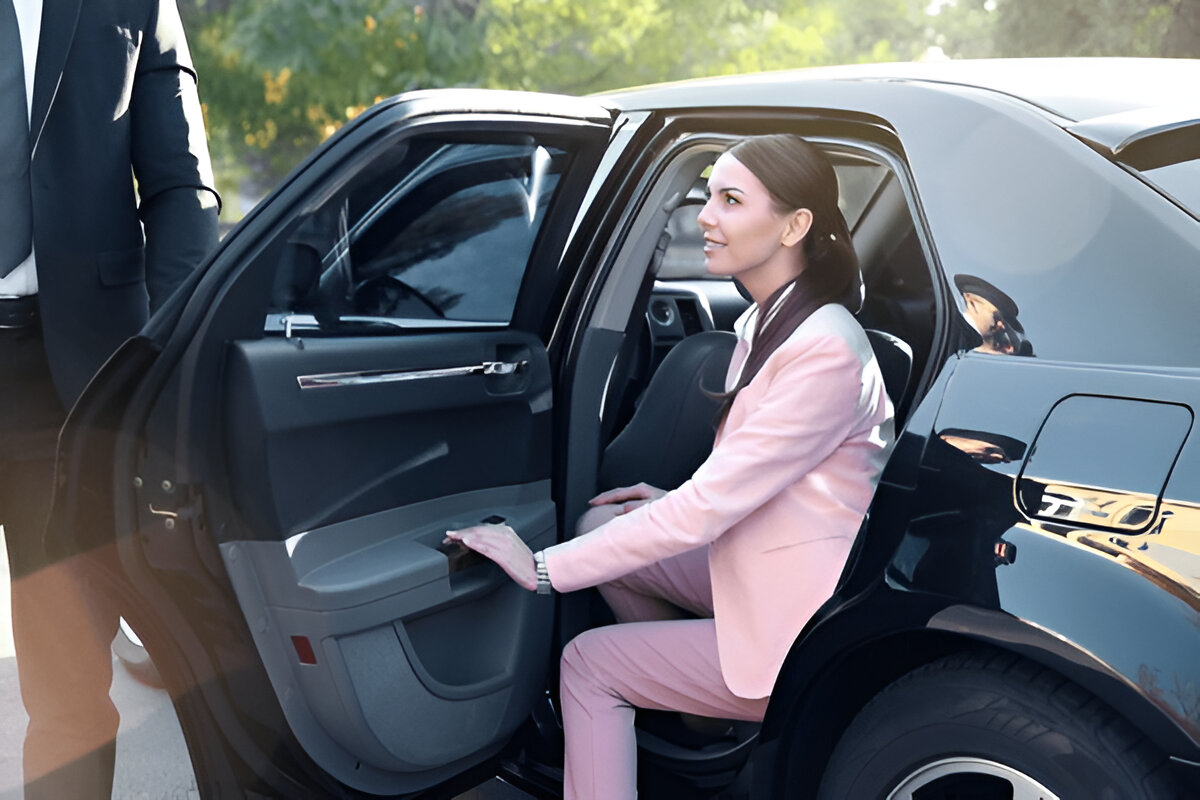 Pembe takım elbiseli kadın VIP araca binerken yanında duran şoför